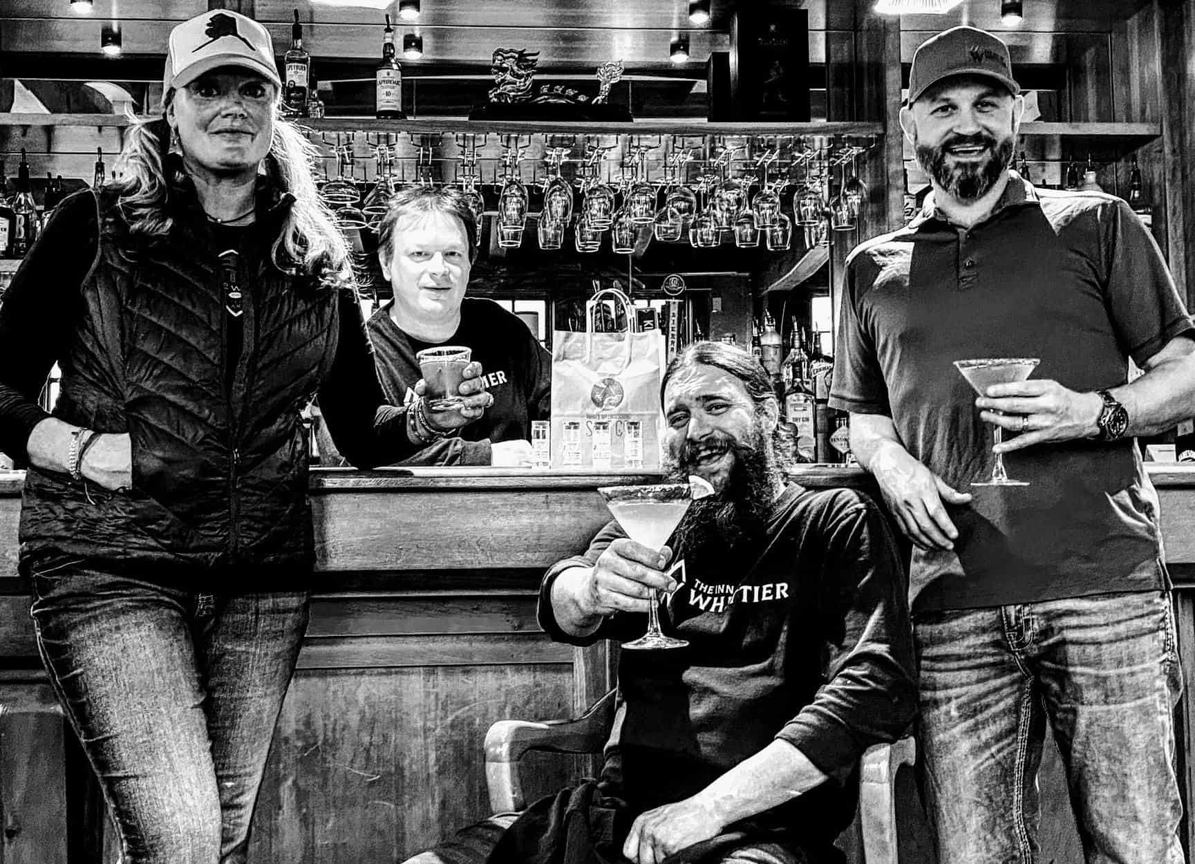 black and white photo of four adults at a bar